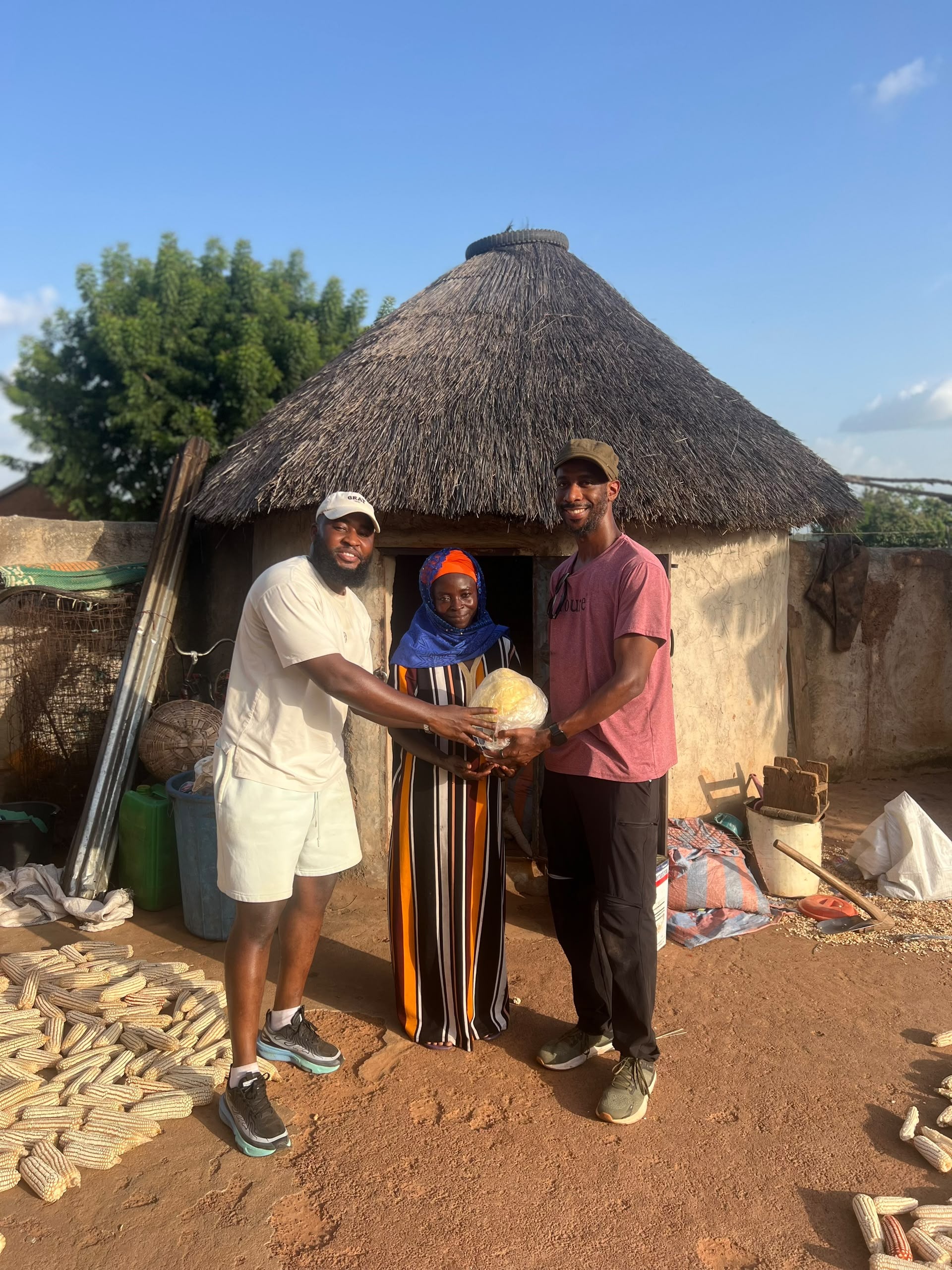 Community group holding a shea butter ball outside a hut in Ghana